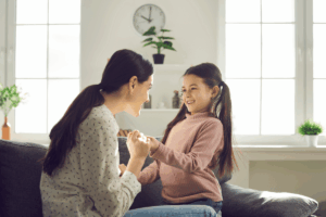 A mother engaging with her daughter, both are smiling, during a parent visit in NY.