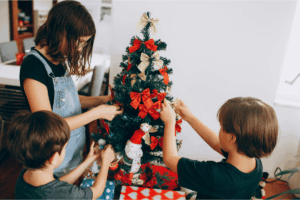 3 Children decorate a small Christmas tree around the holidays where custody disagreements are common.